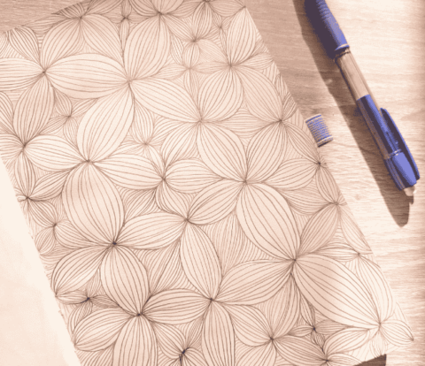 Dessin DIY zen art floral en noir et blanc dans un carnet, motif répétitif relaxant et créatif.