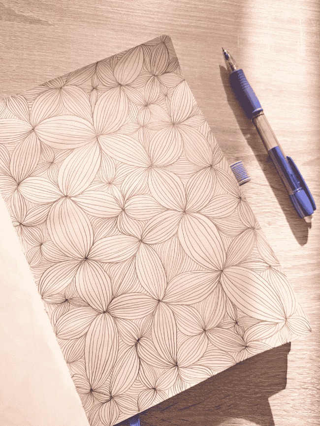 Dessin DIY zen art floral en noir et blanc dans un carnet, motif répétitif relaxant et créatif.