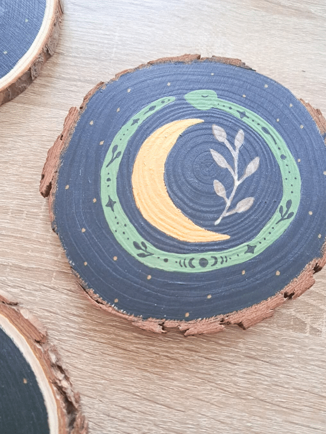 Rondin de bois peint d’une lune dorée entourée de feuillage, idée déco DIY d’Halloween