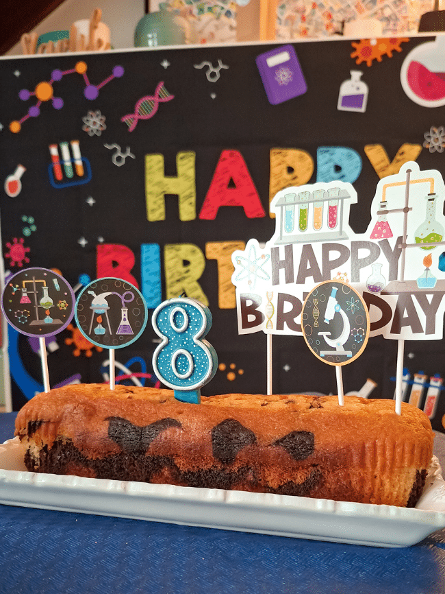 Gâteau d’anniversaire à thème scientifique avec bougie 8 ans et décorations laboratoire.